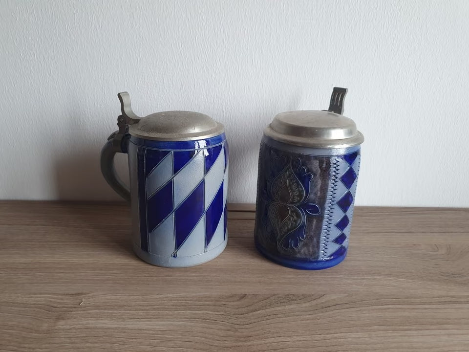 Zwei blau-graue Steinzeug-Bierkrüge mit Zinndeckeln – links Rautendekor, rechts florales Relief