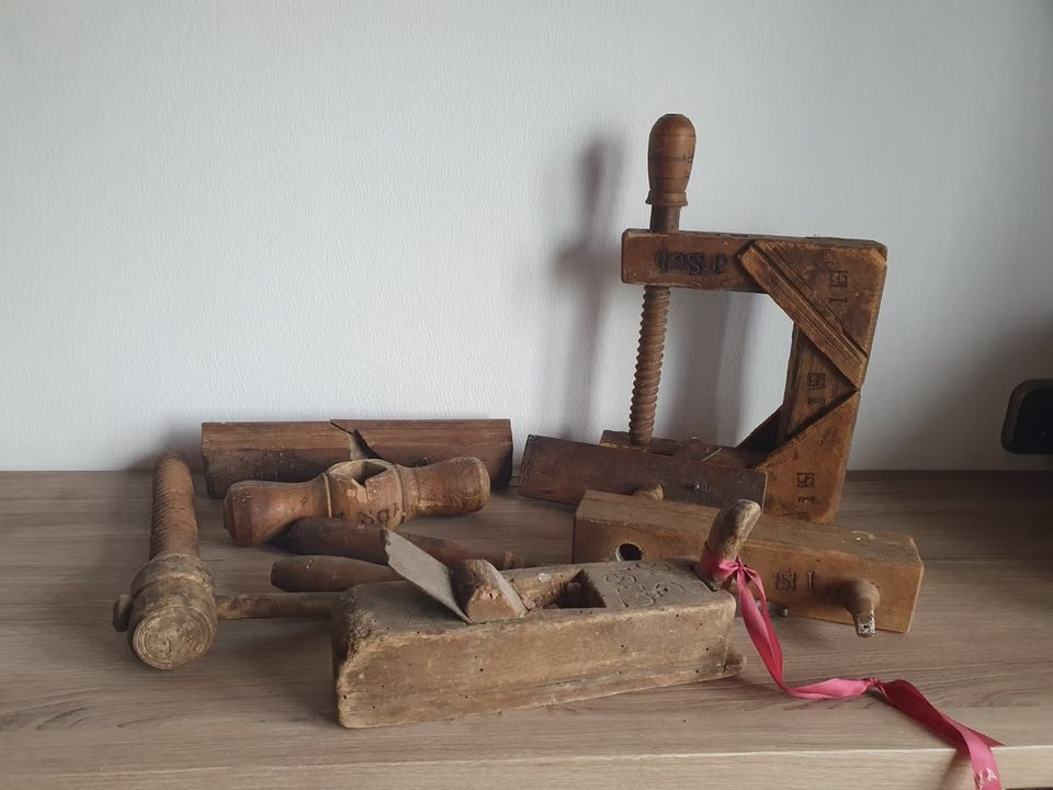 Gesamtansicht des alten Schreinerwerkzeugsets mit Holzhobeln, Schraubzwinge und weiteren Werkzeugen