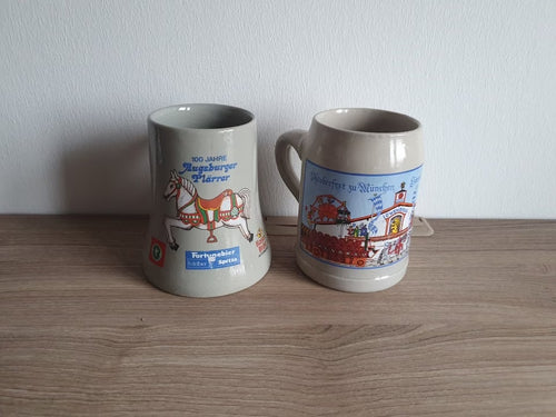 Zweierset Steinzeug-Sammlerkrüge – 100 Jahre Augsburger Plärrer mit Karussellpferd und Oktoberfest München mit Löwenbräu-Motiv